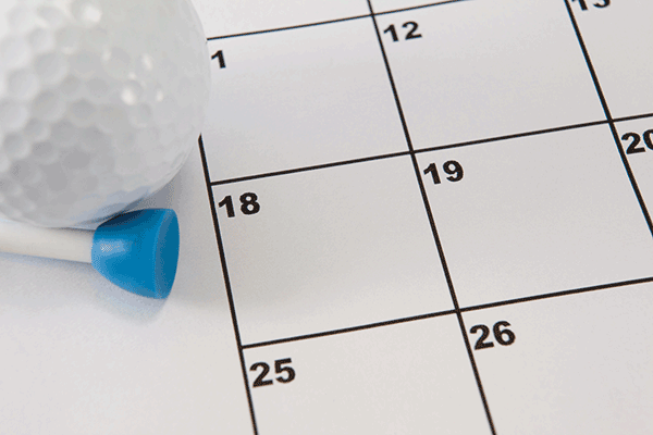 A golf ball sites on top of a calendar.