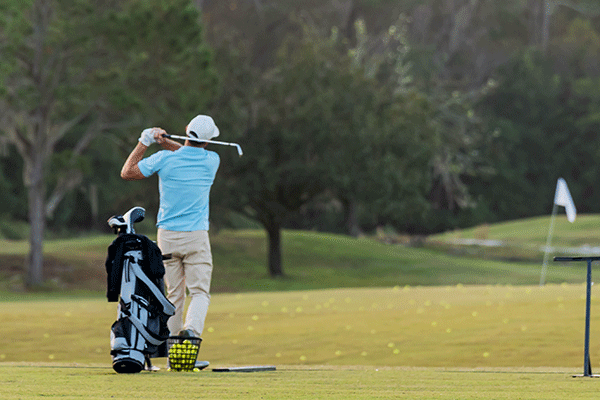 Golfer swinging club at the driving range