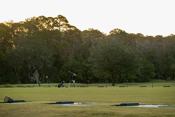A lone golfer on the driving range swinging his golf club