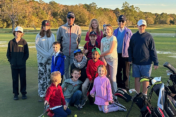 Adults and children pose for a photo on a golf course.