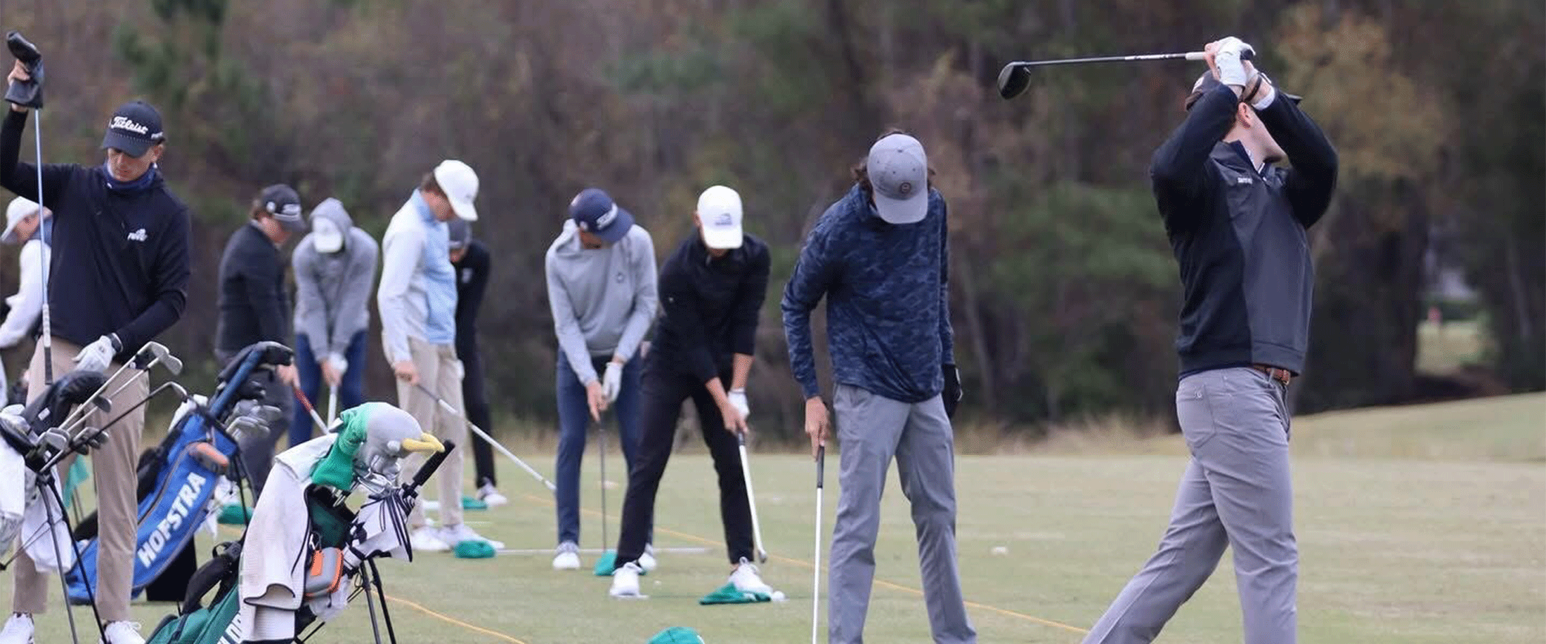 several golfers lined up practicing their swing